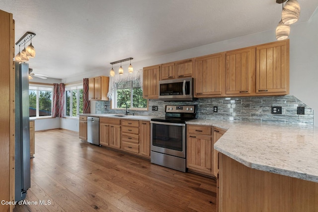 9067 W Coeur D Alene Dr, Spirit Lake, ID 83869 - kitchen with stainless steel appliances, light countertops, dark wood-style floors, tasteful backsplash, and pendant lighting