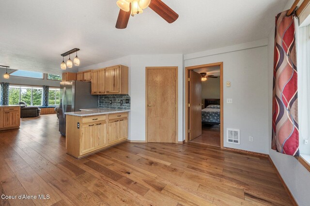 9067 W Coeur D Alene Dr, Spirit Lake, ID 83869 - kitchen with ceiling fan, stainless steel fridge, wood finished floors, light countertops, and a peninsula