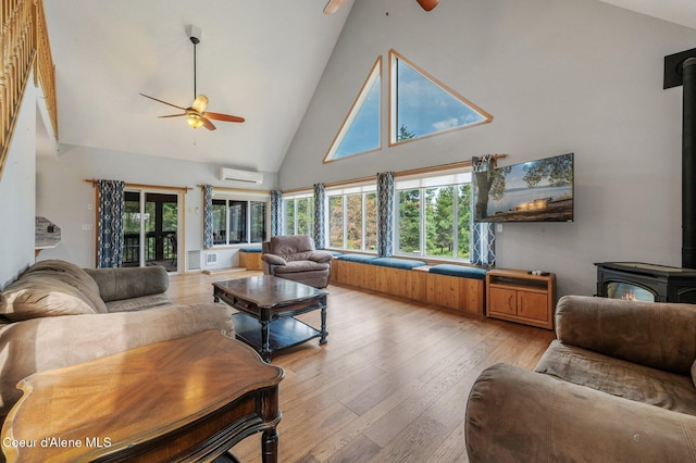 9067 W Coeur D Alene Dr, Spirit Lake, ID 83869 - living area featuring a wood stove, a ceiling fan, a wall mounted AC, high vaulted ceiling, and plenty of natural light