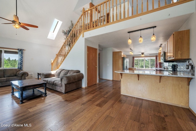 9067 W Coeur D Alene Dr, Spirit Lake, ID 83869 - living room with a ceiling fan, a towering ceiling, dark wood-style floors, stairs, and a skylight