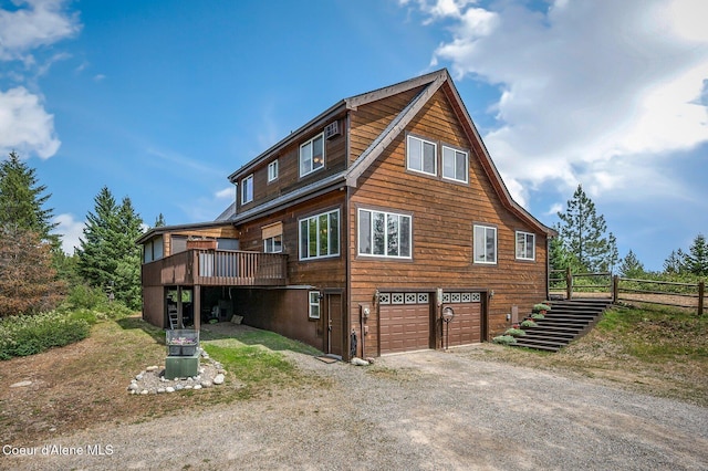 9067 W Coeur D Alene Dr, Spirit Lake, ID 83869 - view of side of property featuring a garage, dirt driveway, a wooden deck, and stairway