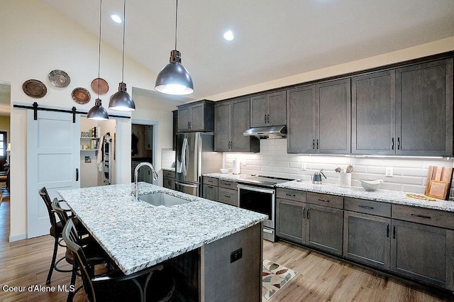 2052 W Bernard Dr, Coeur Dalene, ID 83815 - kitchen with stainless steel appliances, under cabinet range hood, light stone counters, light wood finished floors, and high vaulted ceiling