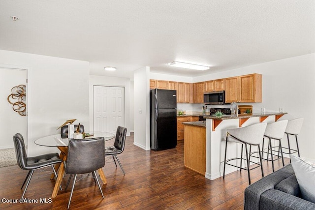 310 N Promenade Loop # 210, Post Falls, ID 83854 - kitchen with freestanding refrigerator, stainless steel microwave, a peninsula, a kitchen bar, and dark wood-style floors
