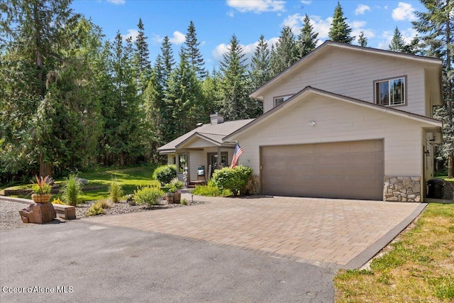 438 Berry Hl, Cocolalla, ID 83813 - view of front of property featuring decorative driveway, an attached garage, stone siding, a chimney, and covered porch