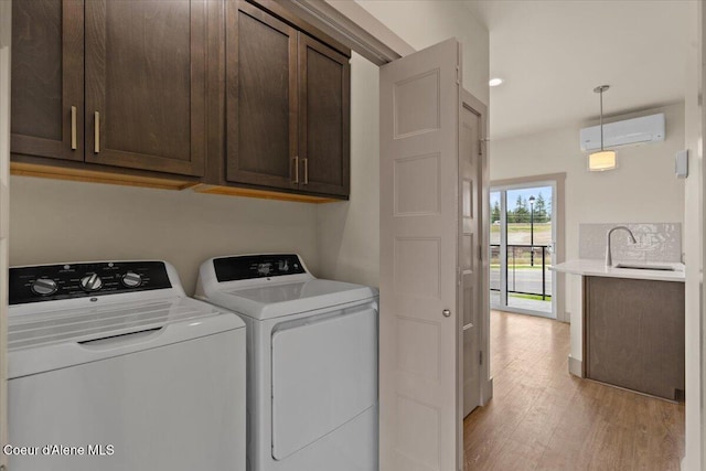 3026 Suzanne C, Coeur Dalene, ID 83815 - washroom featuring a wall unit AC, cabinet space, light wood-style flooring, and washing machine and clothes dryer