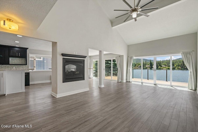 1922 E Rodkey Dr, Post Falls, ID 83854 - unfurnished living room featuring high vaulted ceiling, a multi sided fireplace, a ceiling fan, dark wood-type flooring, and healthy amount of natural light