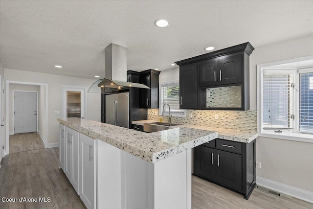 1922 E Rodkey Dr, Post Falls, ID 83854 - kitchen with island exhaust hood, backsplash, stainless steel refrigerator, plenty of natural light, and recessed lighting