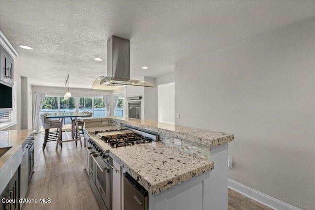 1922 E Rodkey Dr, Post Falls, ID 83854 - kitchen with island range hood, range with two ovens, light wood finished floors, a center island, and a textured ceiling