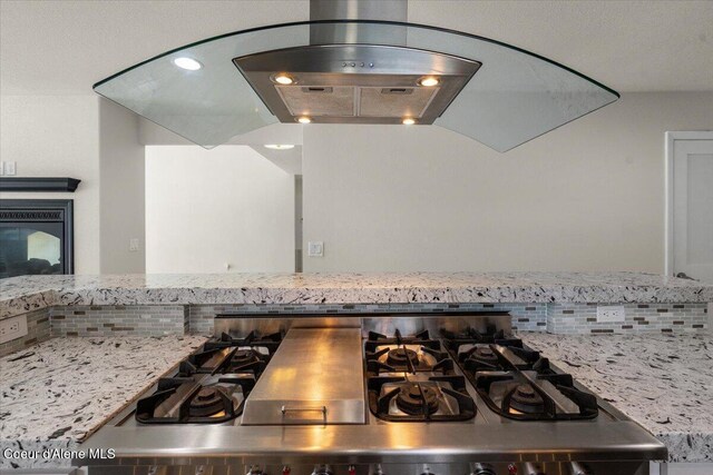 1922 E Rodkey Dr, Post Falls, ID 83854 - kitchen view of light stone counters, decorative backsplash, stainless steel gas cooktop, and range hood