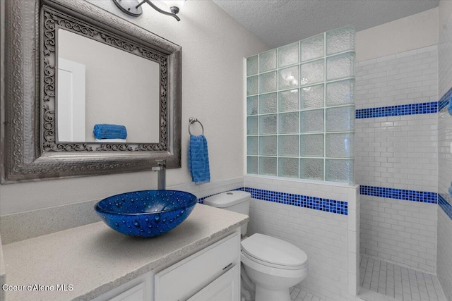 1922 E Rodkey Dr, Post Falls, ID 83854 - bathroom featuring walk in shower, vanity, a textured ceiling, and tile walls