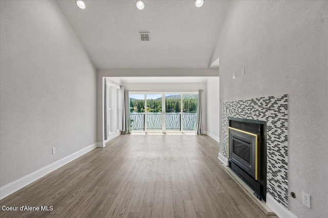 1922 E Rodkey Dr, Post Falls, ID 83854 - unfurnished living room with a fireplace, lofted ceiling, a water view, wood finished floors, and a textured ceiling