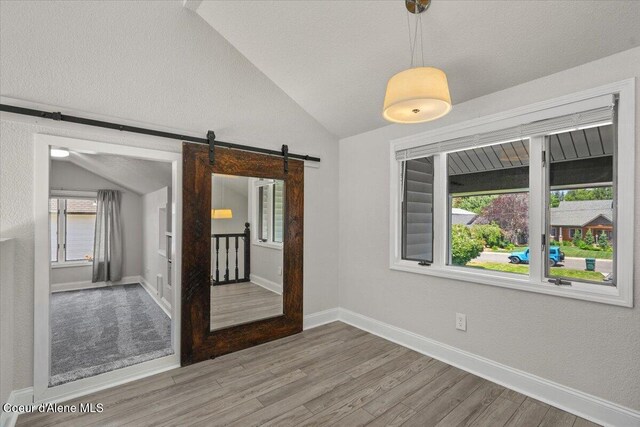 1922 E Rodkey Dr, Post Falls, ID 83854 - unfurnished room featuring vaulted ceiling, a barn door, and wood finished floors