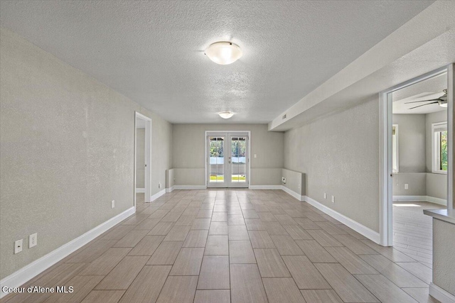 1922 E Rodkey Dr, Post Falls, ID 83854 - spare room with a textured ceiling, french doors, a textured wall, a ceiling fan, and wood tiled floors