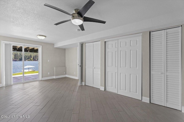 1922 E Rodkey Dr, Post Falls, ID 83854 - unfurnished bedroom featuring access to outside, a textured ceiling, multiple closets, wood finished floors, and ceiling fan
