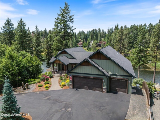 11667 N Eastshore Dr, Hayden, ID 83835 - craftsman-style house featuring board and batten siding, asphalt driveway, a garage, a view of trees, and stone siding