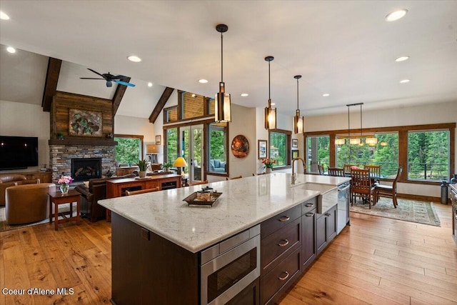 11667 N Eastshore Dr, Hayden, ID 83835 - kitchen featuring appliances with stainless steel finishes, light wood-style flooring, healthy amount of natural light, beam ceiling, and open floor plan