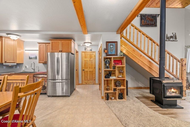 20264 Coeur Dalene River Rd, Kingston, ID 83839 - kitchen with freestanding refrigerator, beam ceiling, dishwasher, a wood stove, and light brown cabinets