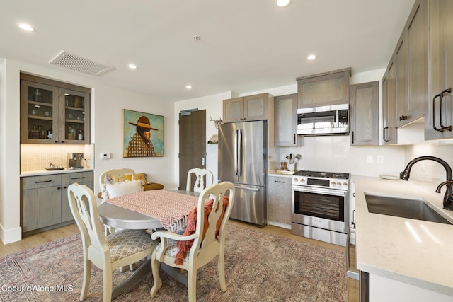 201 N 1st St # 1006, Coeur Dalene, ID 83814 - kitchen featuring stainless steel appliances, light wood-style floors, backsplash, recessed lighting, and glass insert cabinets