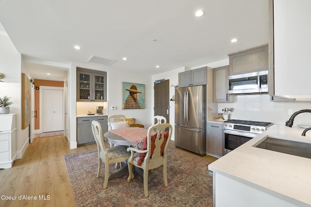 201 N 1st St # 1006, Coeur Dalene, ID 83814 - kitchen featuring stainless steel appliances, light wood-style floors, recessed lighting, gray cabinetry, and glass insert cabinets