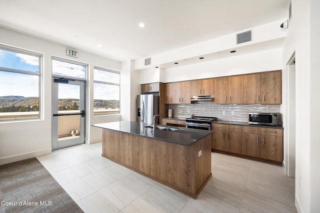 201 N 1st St # 1006, Coeur Dalene, ID 83814 - kitchen with appliances with stainless steel finishes, tasteful backsplash, an island with sink, dark stone countertops, and recessed lighting