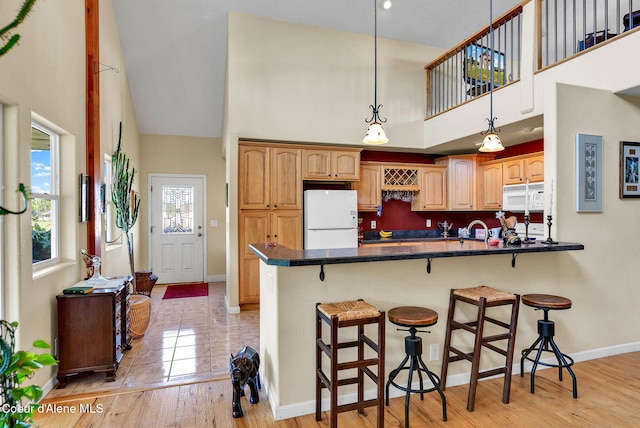 1600 Shepherd Rd, Saint Maries, ID 83861 - kitchen featuring white appliances, a high ceiling, a kitchen bar, a peninsula, and hanging light fixtures