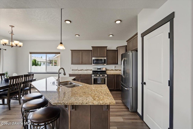 1824 E Warbler Ln, Post Falls, ID 83854 - kitchen featuring stainless steel appliances, a center island with sink, dark wood-style flooring, a chandelier, and light stone counters