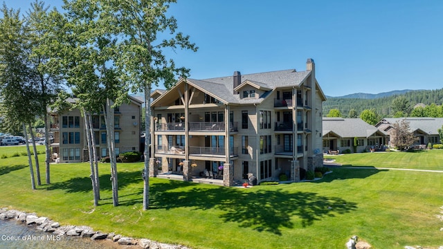 653 Dover Bay Pkwy Unit 101, Dover, ID 83825 - rear view of house featuring a balcony, a mountain view, a lawn, and a chimney