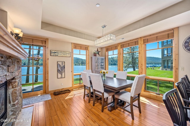 653 Dover Bay Pkwy Unit 101, Dover, ID 83825 - dining space with light wood finished floors, a water and mountain view, a tray ceiling, and a fireplace