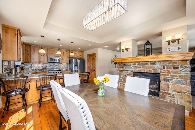 653 Dover Bay Pkwy Unit 101, Dover, ID 83825 - dining area with a tray ceiling, light wood-style floors, a fireplace, and recessed lighting