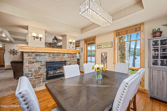 653 Dover Bay Pkwy Unit 101, Dover, ID 83825 - dining space featuring a tray ceiling, a stone fireplace, wood-type flooring, a chandelier, and a water view