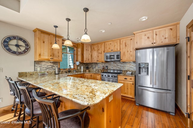 653 Dover Bay Pkwy Unit 101, Dover, ID 83825 - kitchen featuring appliances with stainless steel finishes, a peninsula, tasteful backsplash, and hardwood / wood-style floors