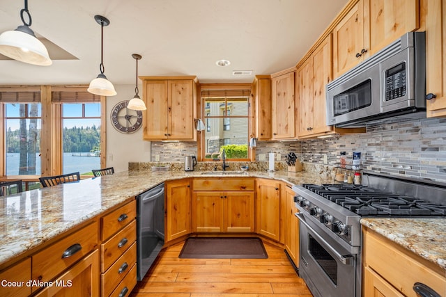 653 Dover Bay Pkwy Unit 101, Dover, ID 83825 - kitchen featuring stainless steel appliances, light wood-style flooring, tasteful backsplash, light stone countertops, and pendant lighting