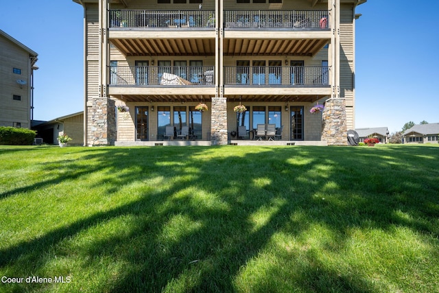 653 Dover Bay Pkwy Unit 101, Dover, ID 83825 - rear view of house with a balcony, stone siding, and a yard