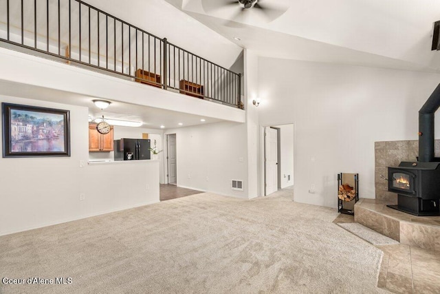 116 Mathews Ridge Rd, Priest River, ID 83856 - unfurnished living room featuring carpet floors, ceiling fan, a wood stove, and a high ceiling