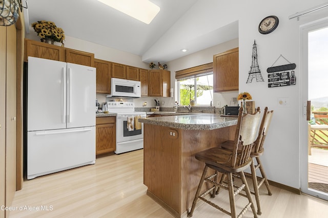 635 N Divot Ave, Post Falls, ID 83854 - kitchen with white appliances, a peninsula, vaulted ceiling, light wood finished floors, and brown cabinetry