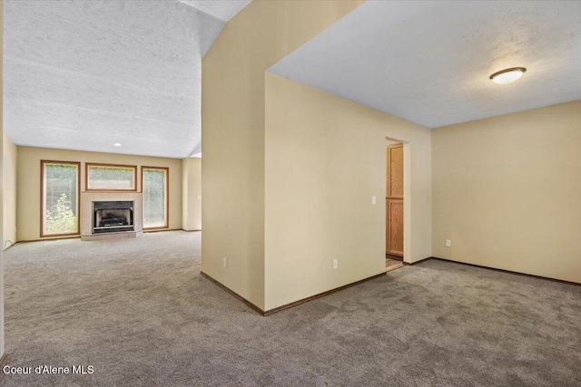 879 E Cloverleaf Dr, Hayden, ID 83835 - unfurnished living room featuring carpet, a textured ceiling, and a tile fireplace