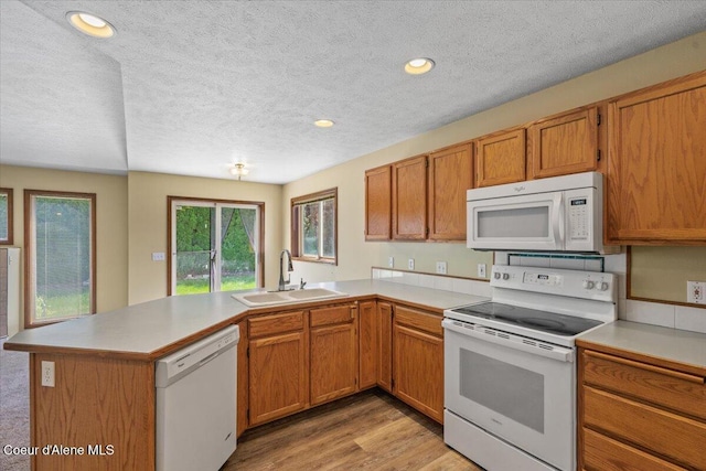 879 E Cloverleaf Dr, Hayden, ID 83835 - kitchen with white appliances, a peninsula, a textured ceiling, light countertops, and brown cabinetry