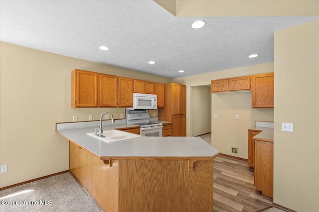 879 E Cloverleaf Dr, Hayden, ID 83835 - kitchen featuring white appliances, a peninsula, light countertops, recessed lighting, and brown cabinetry