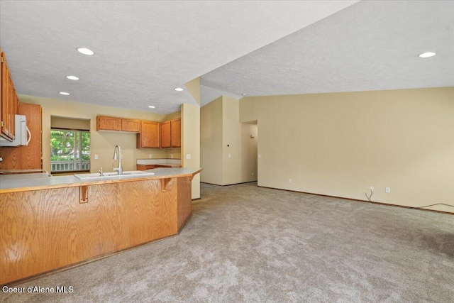 879 E Cloverleaf Dr, Hayden, ID 83835 - kitchen featuring white microwave, a peninsula, light colored carpet, a kitchen breakfast bar, and recessed lighting