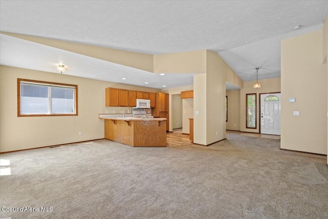 879 E Cloverleaf Dr, Hayden, ID 83835 - kitchen featuring white microwave, a peninsula, light carpet, a breakfast bar, and vaulted ceiling