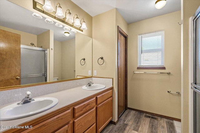 879 E Cloverleaf Dr, Hayden, ID 83835 - bathroom featuring wood finished floors, double vanity, and a shower with shower door