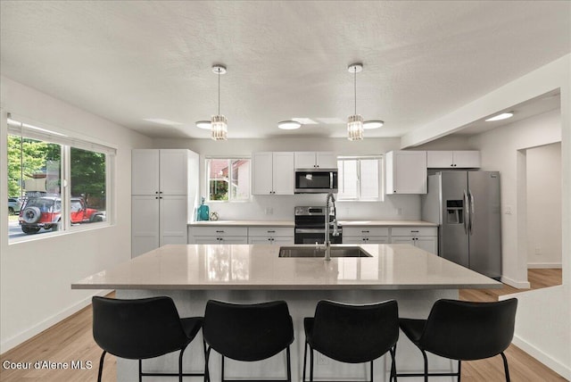 202 S 18th St, Coeur Dalene, ID 83814 - kitchen with stainless steel appliances, a kitchen breakfast bar, light countertops, white cabinetry, and light wood-style floors
