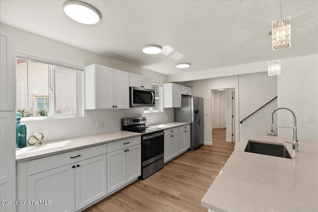 202 S 18th St, Coeur Dalene, ID 83814 - kitchen featuring appliances with stainless steel finishes, light countertops, light wood-style floors, white cabinetry, and hanging light fixtures