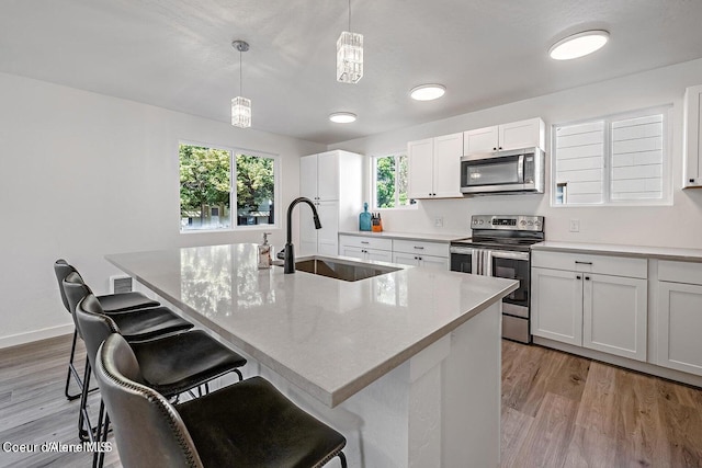 202 S 18th St, Coeur Dalene, ID 83814 - kitchen with stainless steel appliances, light wood-type flooring, a breakfast bar, white cabinetry, and pendant lighting