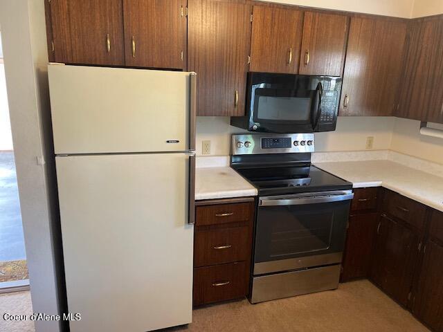 204 W Oak Ave, Osburn, ID 83849 - kitchen with freestanding refrigerator, black microwave, stainless steel range with electric stovetop, and light countertops