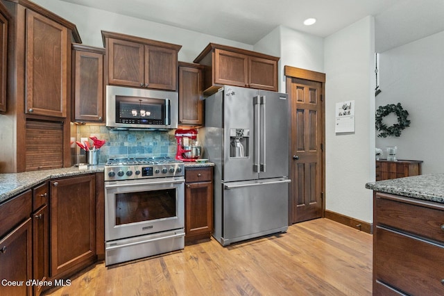 1431 W Ashmont Way, Coeur Dalene, ID 83815 - kitchen with appliances with stainless steel finishes, tasteful backsplash, light stone counters, light wood-type flooring, and recessed lighting