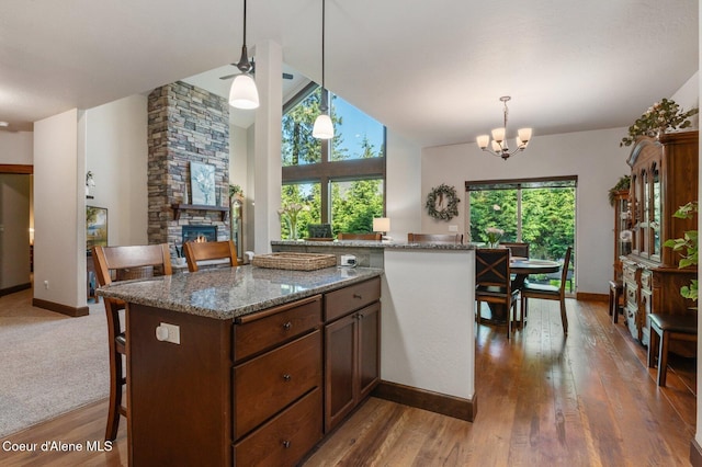 1431 W Ashmont Way, Coeur Dalene, ID 83815 - kitchen with wood finished floors, a stone fireplace, hanging light fixtures, a chandelier, and dark stone countertops