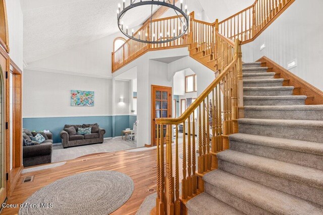 740 N Dundee Dr, Post Falls, ID 83854 - stairs with wood finished floors, high vaulted ceiling, a chandelier, and a textured ceiling