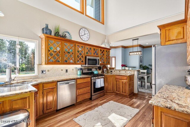 740 N Dundee Dr, Post Falls, ID 83854 - kitchen with stainless steel appliances, a towering ceiling, a peninsula, brown cabinetry, and decorative backsplash