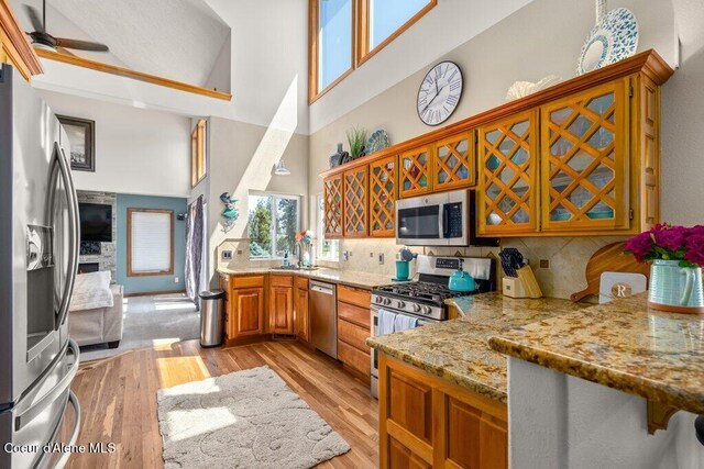 740 N Dundee Dr, Post Falls, ID 83854 - kitchen with appliances with stainless steel finishes, a high ceiling, brown cabinetry, light stone counters, and backsplash